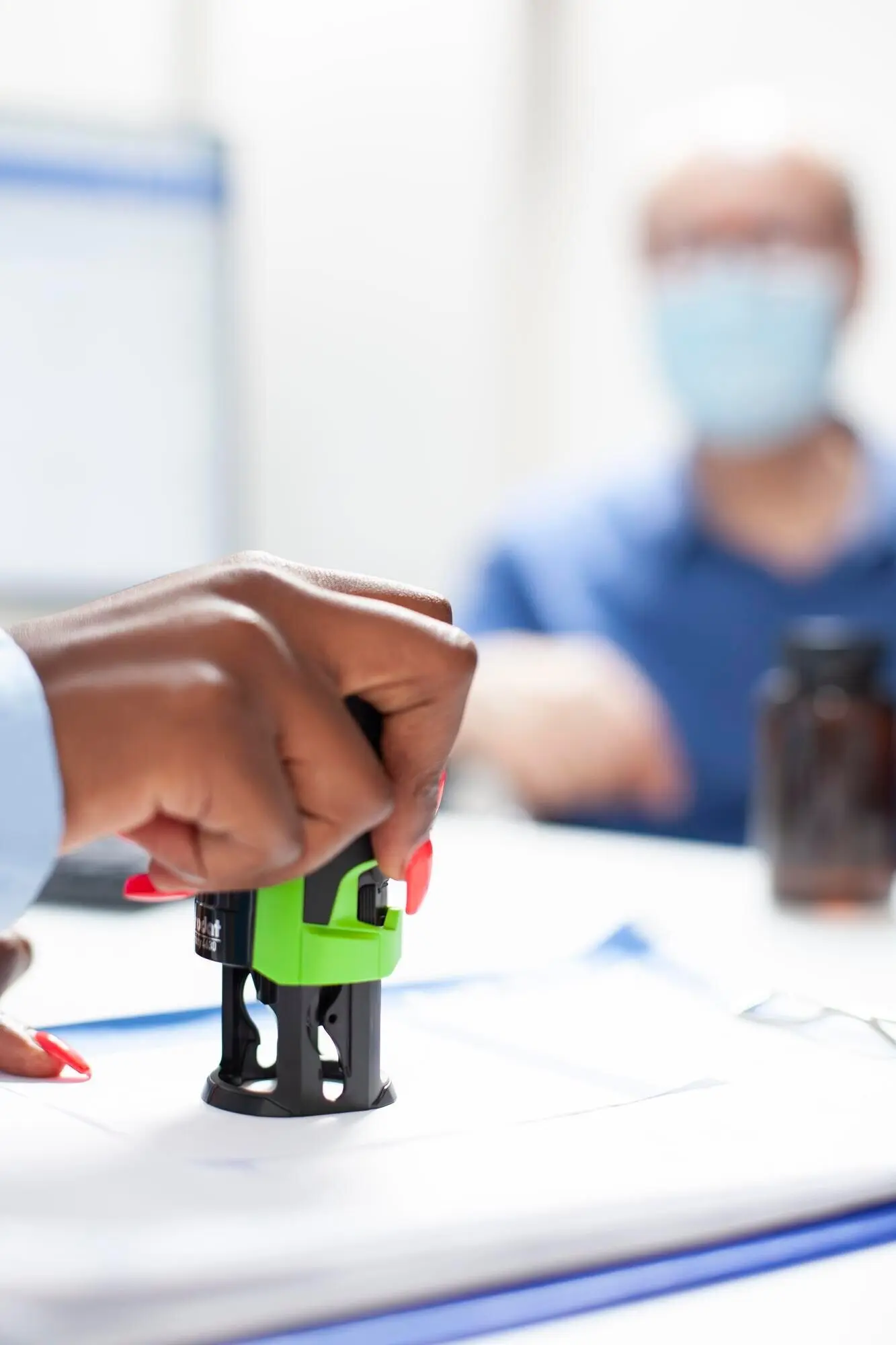 Врач ставит печать на документ для пожилого пациента.